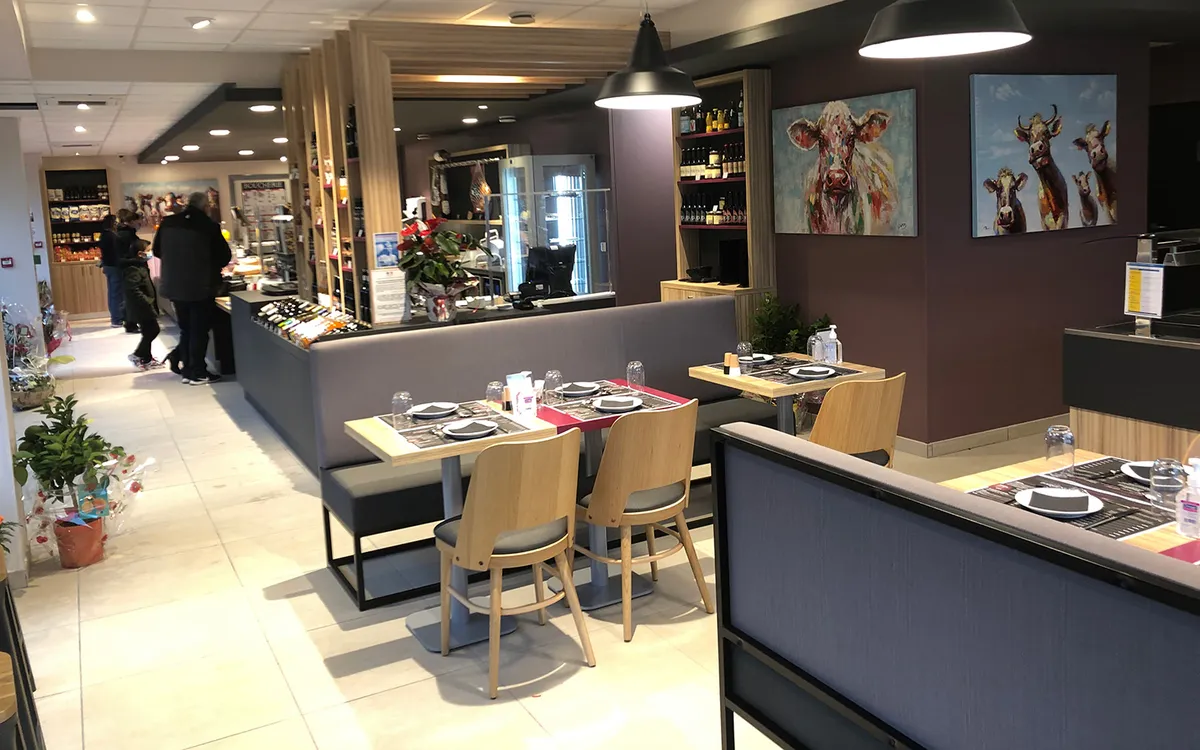 Salle de restaurant amenagee au-dessus d'une boucherie, suspensions noires et spots encastres