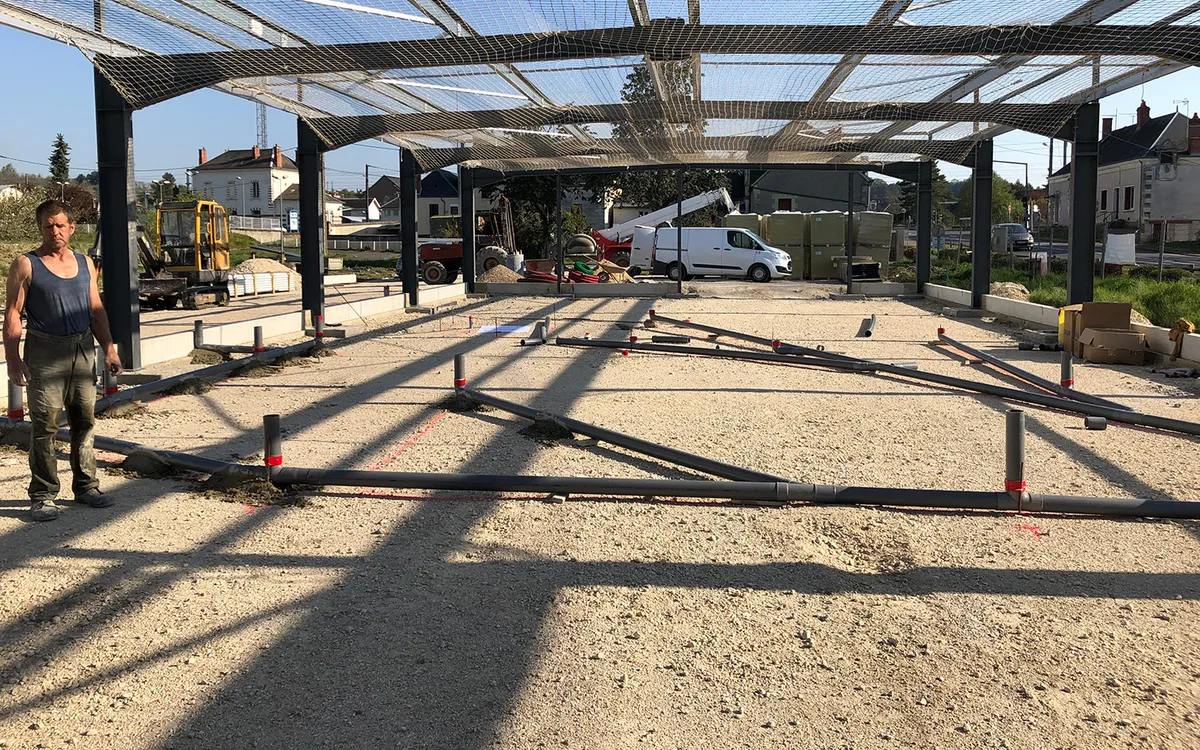 Chantier de construction sous charpente metallique, avec un ouvrier et un utilitaire de l'entreprise