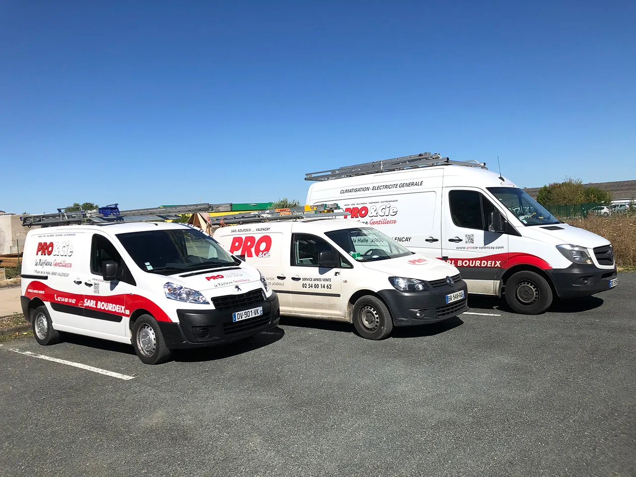 Les trois utilitaires floques de la SARL Bourdeix alignes devant le depot, sous un ciel bleu