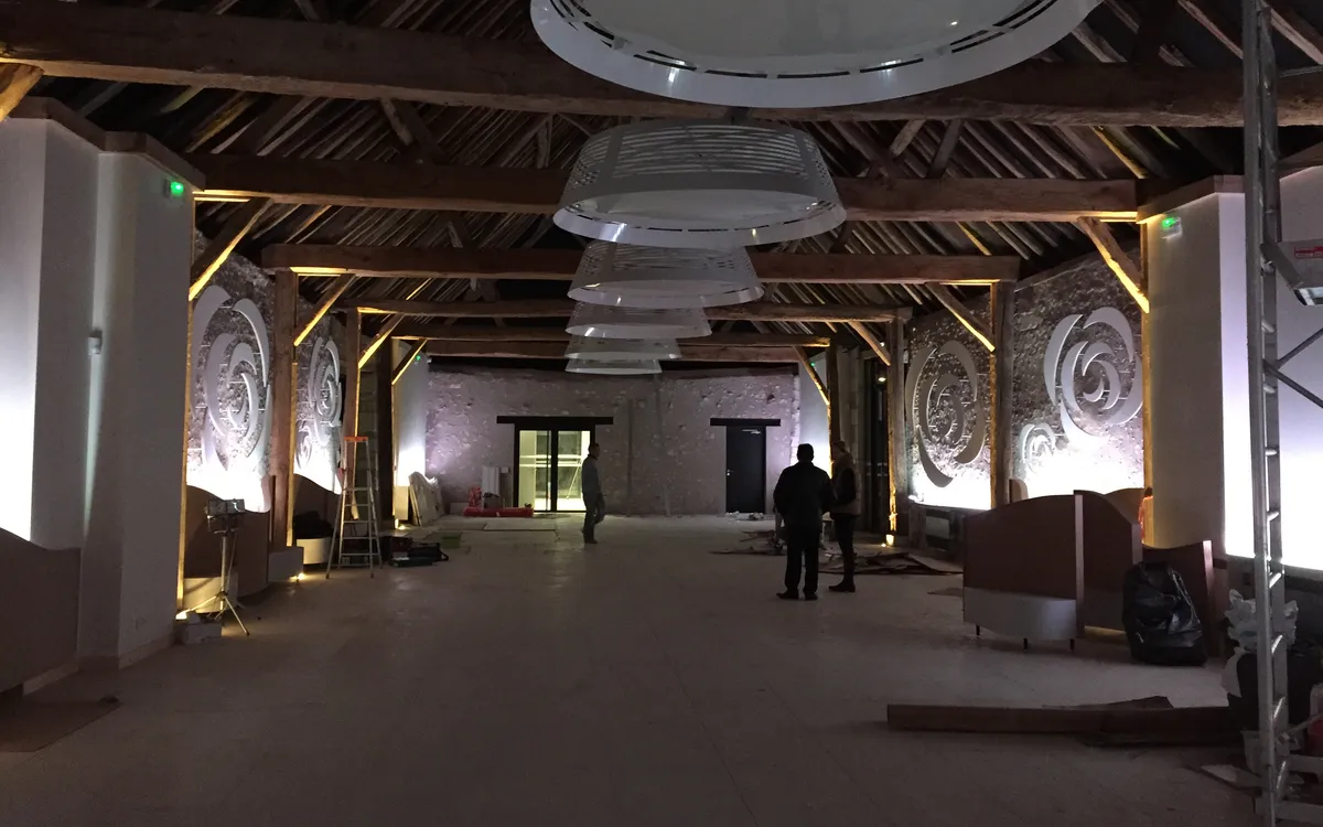 Grange renovee apres travaux : charpente ancienne mise en lumiere et suspensions design