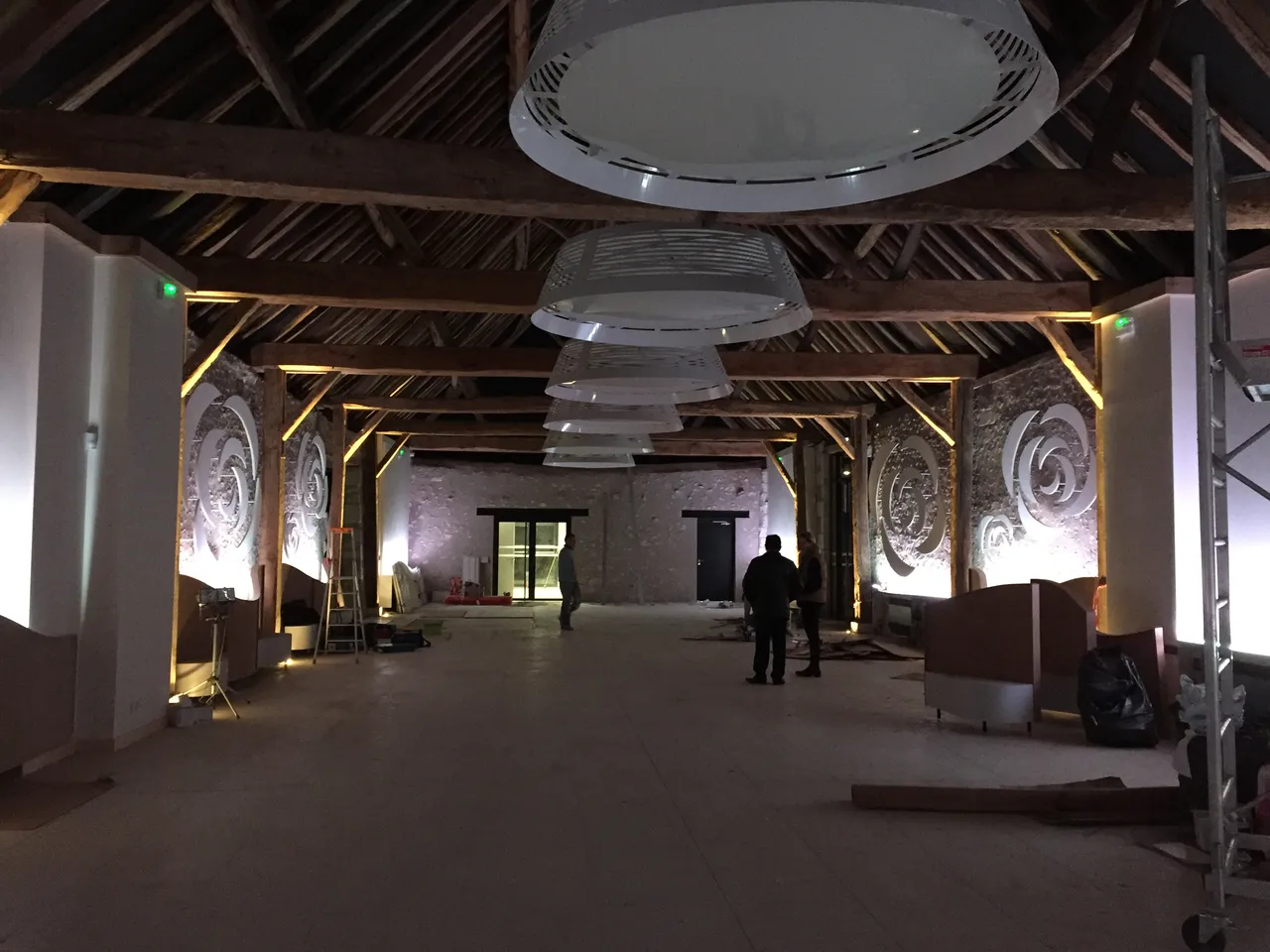 Grange renovee apres travaux : charpente ancienne mise en lumiere et suspensions design