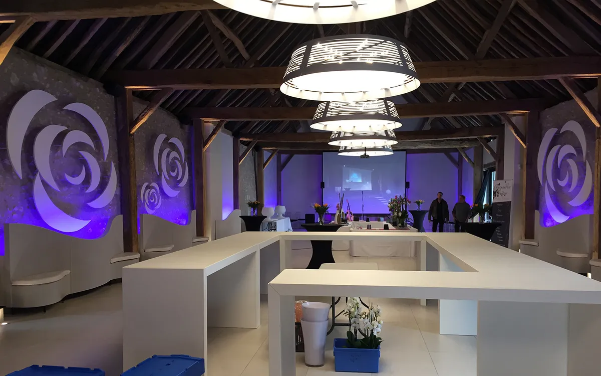 Salle de reception sous charpente ancienne avec mise en lumiere coloree et lustres contemporains